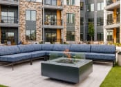 Thumbnail 61 of 65 - an outdoor patio with couches and a fire pit in front of an apartment building at Stonehill at West Orange, New Jersey