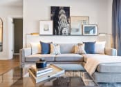 Thumbnail 18 of 65 - a living room with a gray couch and a glass coffee table at Stonehill at West Orange, West Orange