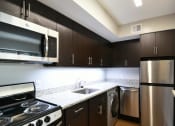Thumbnail 9 of 27 - a kitchen with dark cabinets and stainless steel appliances