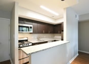 Thumbnail 10 of 27 - a kitchen with white countertops and dark wood cabinets