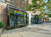 Thumbnail 14 of 17 - a store front with a rainbow sign in the window at 1841 Columbia Road Apartments, Washington, DC
