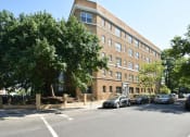 Thumbnail 27 of 27 - a large brick building with cars parked in front of it