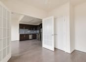Thumbnail 9 of 13 - an empty living room with a kitchen in the background