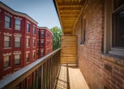 Thumbnail 6 of 25 - a balcony with a wooden railing and a brick building in the background
