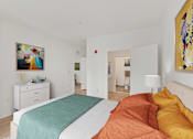 Thumbnail 28 of 66 - A bedroom with a bed, nightstand, and a painting on the wall.