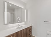 Thumbnail 45 of 66 - A modern bathroom with a sink, mirror, and wooden cabinets.