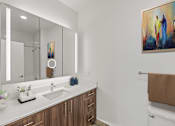 Thumbnail 29 of 66 - A bathroom with a large mirror, a sink, and a painting on the wall.
