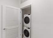 Thumbnail 43 of 66 - A white door is open to a small laundry room with a washer and dryer.