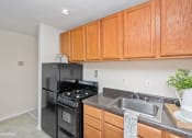 Thumbnail 6 of 14 - a kitchen with wood cabinets and black appliances