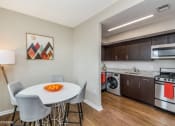 Thumbnail 19 of 27 - a dining area with a table and chairs and a kitchen with a washer and dryer