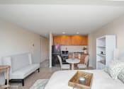Thumbnail 4 of 14 - a bedroom with a bed a table and chairs and a kitchen in the background