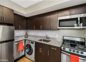 Thumbnail 18 of 27 - a kitchen with brown cabinets and a white stove top oven