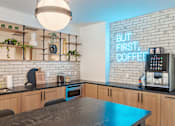 Thumbnail 4 of 47 - Community kitchen with neon coffee sign and appliances at The Yancey Apartments, Charlotte, NC