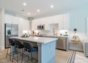 Thumbnail 13 of 47 - Modern kitchen with white cabinets and island seating at The Yancey Apartments, Charlotte, North Carolina