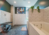 Thumbnail 12 of 47 - Spa bathroom with soaking tub and white brick walls at The Yancey Apartments, Charlotte