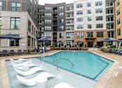 Thumbnail 43 of 47 - Resort style pool with sun shelf loungers and courtyard seating at The Yancey Apartments, North Carolina
