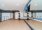 Thumbnail 34 of 47 - Upper level fitness studio with mirrored wall and wood flooring at The Yancey Apartments, Charlotte, 28217