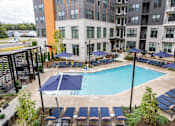 Thumbnail 25 of 47 - Pool deck with lounge chairs and blue umbrellas at The Yancey Apartments, Charlotte, 28217