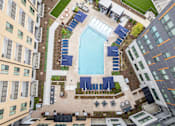 Thumbnail 21 of 47 - Aerial view of pool deck with lounge chairs and cabanas at The Yancey Apartments, Charlotte, NC