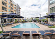 Thumbnail 17 of 47 - Pool area with large umbrellas and surrounding lounge chairs at The Yancey Apartments, Charlotte, North Carolina