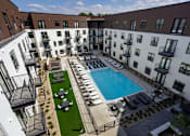 Thumbnail 3 of 30 - A large outdoor pool surrounded by lounge chairs and umbrellas.