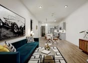 Thumbnail 20 of 30 - A living room with a blue couch and a black and white photo of a race car on the wall at Vintage Edge Nashville Apartments, Nashville, TN