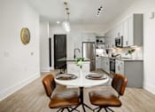 Thumbnail 22 of 30 - A modern kitchen with a dining table set for two at Vintage Edge Nashville Apartments, Tennessee, 37211