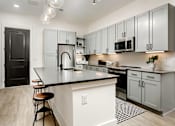 Thumbnail 18 of 30 - A kitchen with a black countertop and white cabinets at Vintage Edge Nashville Apartments, Nashville