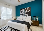 Thumbnail 23 of 30 - A bedroom with a bed, nightstand, and a large abstract painting on the wall at Vintage Edge Nashville Apartments, Nashville, TN