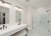 Thumbnail 30 of 30 - A white bathroom with a sink, mirror, toilet, and shower at Vintage Edge Nashville Apartments, Tennessee, 37211