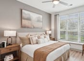 Thumbnail 4 of 41 - A well-lit bedroom with a large bed, a painting on the wall, and a window with blinds at Vintage Raleigh West Apartments, Raleigh, North Carolina