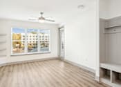 Thumbnail 11 of 41 - A room with a window showing a view of a building and a fan on the ceiling at Vintage Raleigh West Apartments, North Carolina, 27607