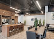 Thumbnail 17 of 41 - A modern kitchen with a dining table and chairs at Vintage Raleigh West Apartments, Raleigh
