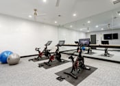 Thumbnail 14 of 30 - A gym with exercise bikes and a television.