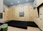 Thumbnail 8 of 30 - A bouldering room with a wooden floor and a wall covered in climbing holds.