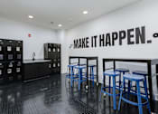 Thumbnail 6 of 30 - A black and white room with blue stools and a wall that says "Make it happen".