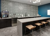 Thumbnail 7 of 30 - A modern kitchen with a bar area and stools.