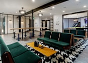 Thumbnail 13 of 30 - A room with green couches and a black and white rug.