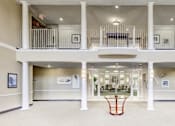 Thumbnail 7 of 11 - the lobby of a large building with a balcony and a table at Windsor Crossing Senior, Suitland Maryland 