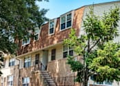 Thumbnail 1 of 3 - A brown building with a tree in front of it at Pleasantview Apartments, Baltimore