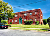 Thumbnail 10 of 10 - a red brick building with a green door and a blue sky in the background