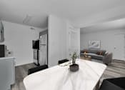 Thumbnail 6 of 15 - A modern kitchen with a white table and a grey couch.