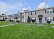 Thumbnail 12 of 15 - A row of modern townhouses with a green lawn in front.