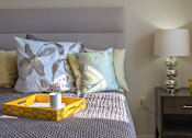 Thumbnail 5 of 10 - A bed with a yellow tray on it and a lamp on the nightstand at Dutch Village Apartments, Baltimore, MD