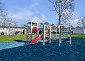 Thumbnail 11 of 15 - A playground with a red slide and a blue rubberized surface.