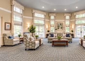 Thumbnail 2 of 29 - A spacious living room with a carpeted floor and large windows.