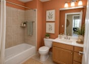 Thumbnail 7 of 10 - A bathroom with orange walls has a white toilet and a white sink.