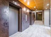 Thumbnail 4 of 29 - A hallway with a brown wall and a white tiled floor at Charlestowne North Apartments, Greenbelt, MD
