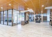 Thumbnail 2 of 29 - A spacious hallway with a tiled floor and glass walls leading to an outdoor area at Charlestowne North Apartments, Greenbelt, MD