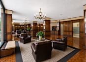 Thumbnail 4 of 17 - A large room with a chandelier and leather chairs.